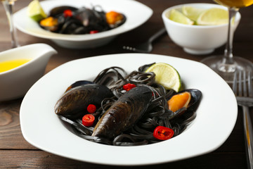 Cooked pasta, mussel and lime on brown wooden background