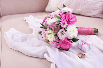 Wedding bouquet and bridesmaid dress on sofa in room