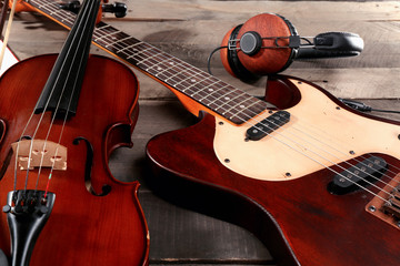 Fototapeta na wymiar Electric guitar, violin, and headphones on wooden background