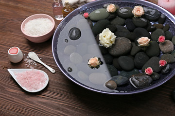 Spa composition of flowers and stones in water on wooden background