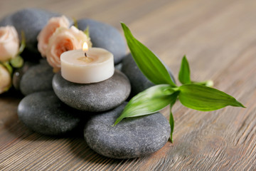 Fototapeta na wymiar Spa composition of candles, flowers and stones on brown wooden background