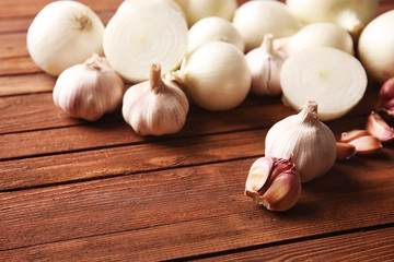 Fresh whole peeled onions with garlic on wooden background
