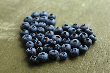 Heart shaped bilberries on old wooden background