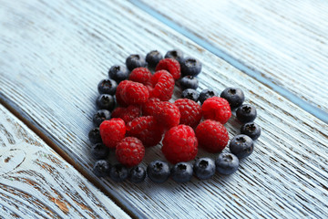 Heart shaped raspberries and blueberries on old wooden background