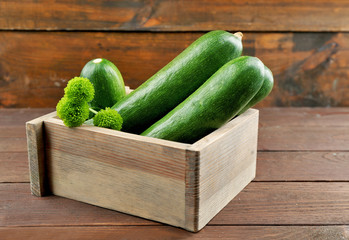 Fresh zucchini in box on wooden background