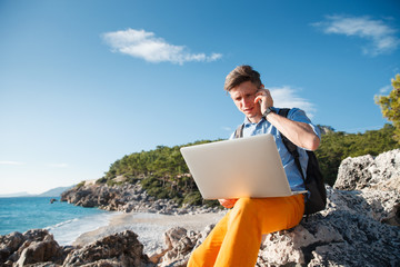 Handsome young male businessman working on the laptop by the seaside