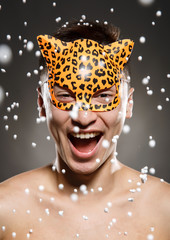 Studio portrait of laughing young man in carnival leopard mask