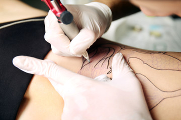 Hands in medicine gloves make tattoo, close up