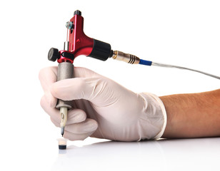 Hand in glove holds red tattoo machine isolated on white background