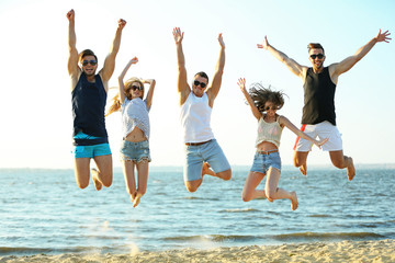 Happy friends jumping at the beach, outdoors