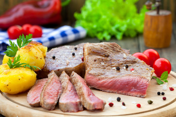 Grilled beef steak with vegetables on wooden board