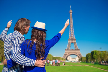 Young happy couple on the Champ de Mars in Paris background the Eiffel Tower
