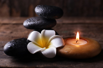 Fototapeta na wymiar Relaxing set of fragipani flower, pebbles and alight candle on wooden background