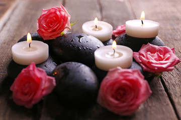Obraz na płótnie Canvas Tenderness relaxing composition with pebbles, roses and candles on wooden background, close up