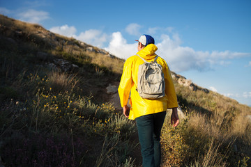 Young male hiker with backpack walking to the mountain