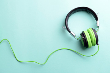 A pair of green-black headphones, on blue background