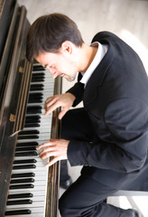 Handsome man in black suit plays piano in the class