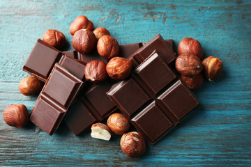 Black chocolate pieces with nuts on color wooden background