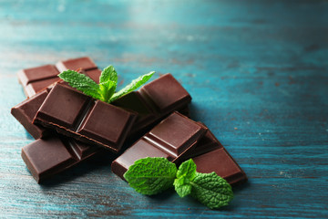 Black chocolate pieces on color wooden background