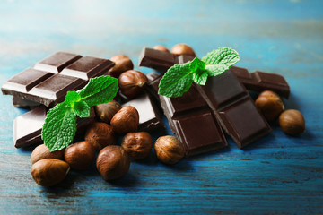 Chocolate pieces with nuts on color wooden background