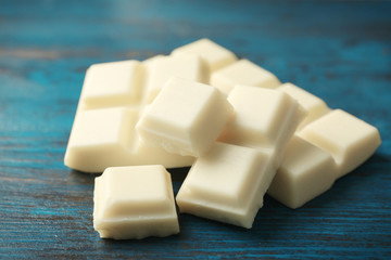 White chocolate pieces on color wooden background