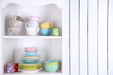 Different clean dishes on wooden shelves