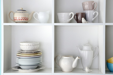 Different clean dishes on wooden shelves