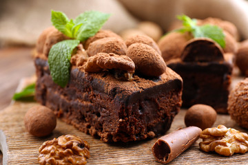 A piece of chocolate cake with walnut and mint on the table, close-up
