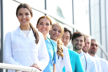 Smiling medics team standing in a row near the clinic