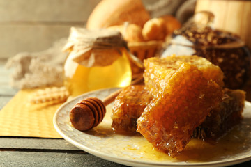 Honeycombs on plate, hot buns in basket on wooden background