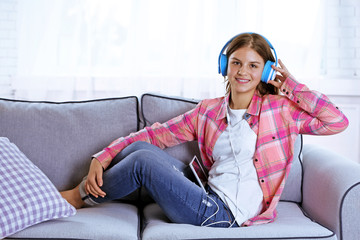 Fototapeta premium Young pretty girl listening to music on the sofa in her room