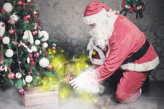 Santa Claus Putting Gift Box Or Present Under Christmas Tree