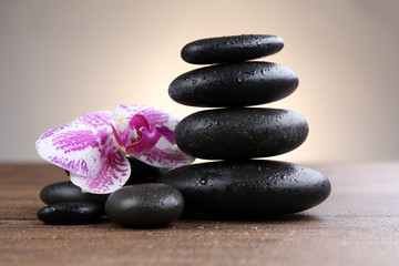 Obraz na płótnie Canvas Black pebbles with orchid on wooden table