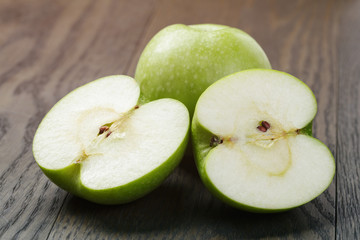 ripe green apples sliced on wood table