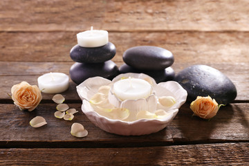 Spa composition of stones, candles and a rose on wooden table