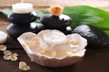 Spa stones, candles and a rose on wooden background