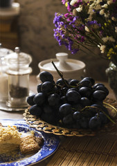 Still life with dark grapes and sweets in vintage style