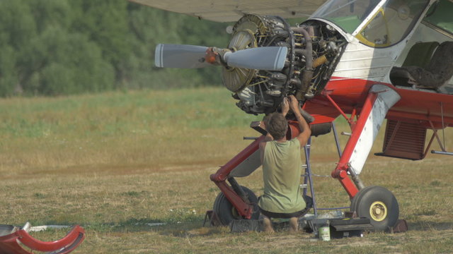 Engineer repairing the engine of the vintage plane on the glade.