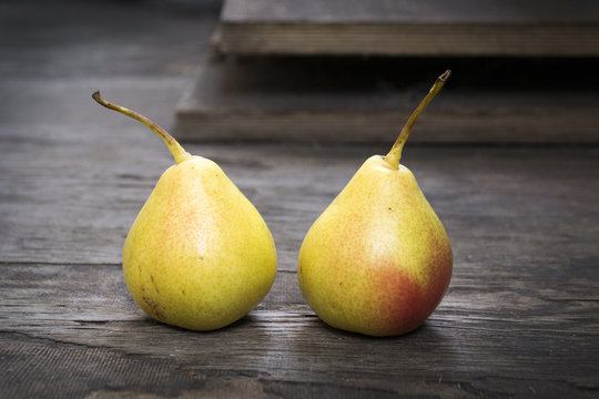 Two yellow pear twins on wooden floor, still life