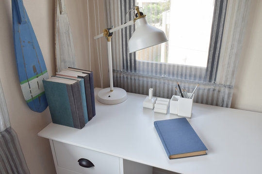 work table with lamp,pencils and books in working room