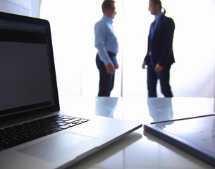 Focus on laptop on the table. Blurred people on background