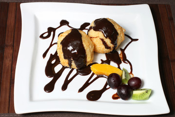 dessert of roast coconut flakes with fruits and chocolate glaze