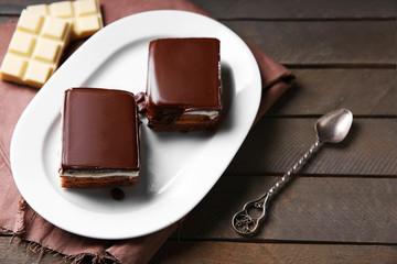 Delicious chocolate brownies on plate, on wooden background
