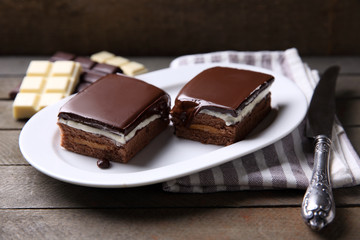 Delicious chocolate brownies on plate, on wooden background