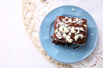 Delicious chocolate brownie on plate on wooden background