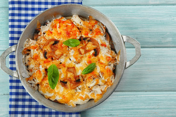 Roasted mushrooms, chicken and cheese gratin in pan, on wooden background