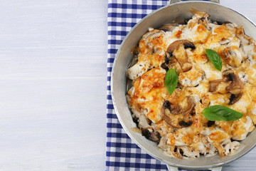 Roasted mushrooms, chicken and cheese gratin in pan, on wooden background