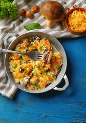Roasted mushrooms, chicken and cheese gratin in pan, on color wooden background