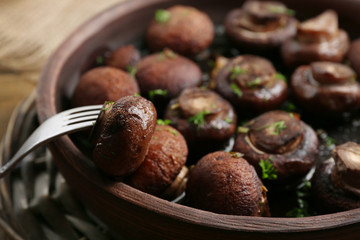 Baked champignons mushrooms with butter, parsley and roasted garlic in brown bowl