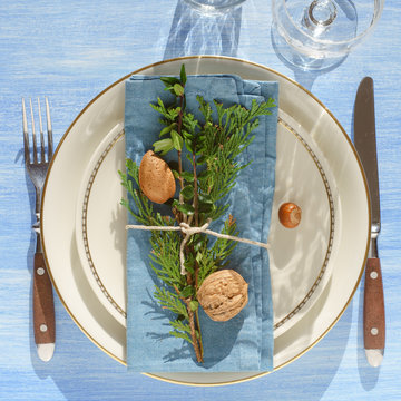 Place setting idea: mix-and-match plates,  evergreen plants, nuts and twine